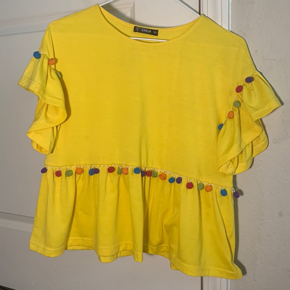 I’m selling a yellow top that has colorful details that make it stand out